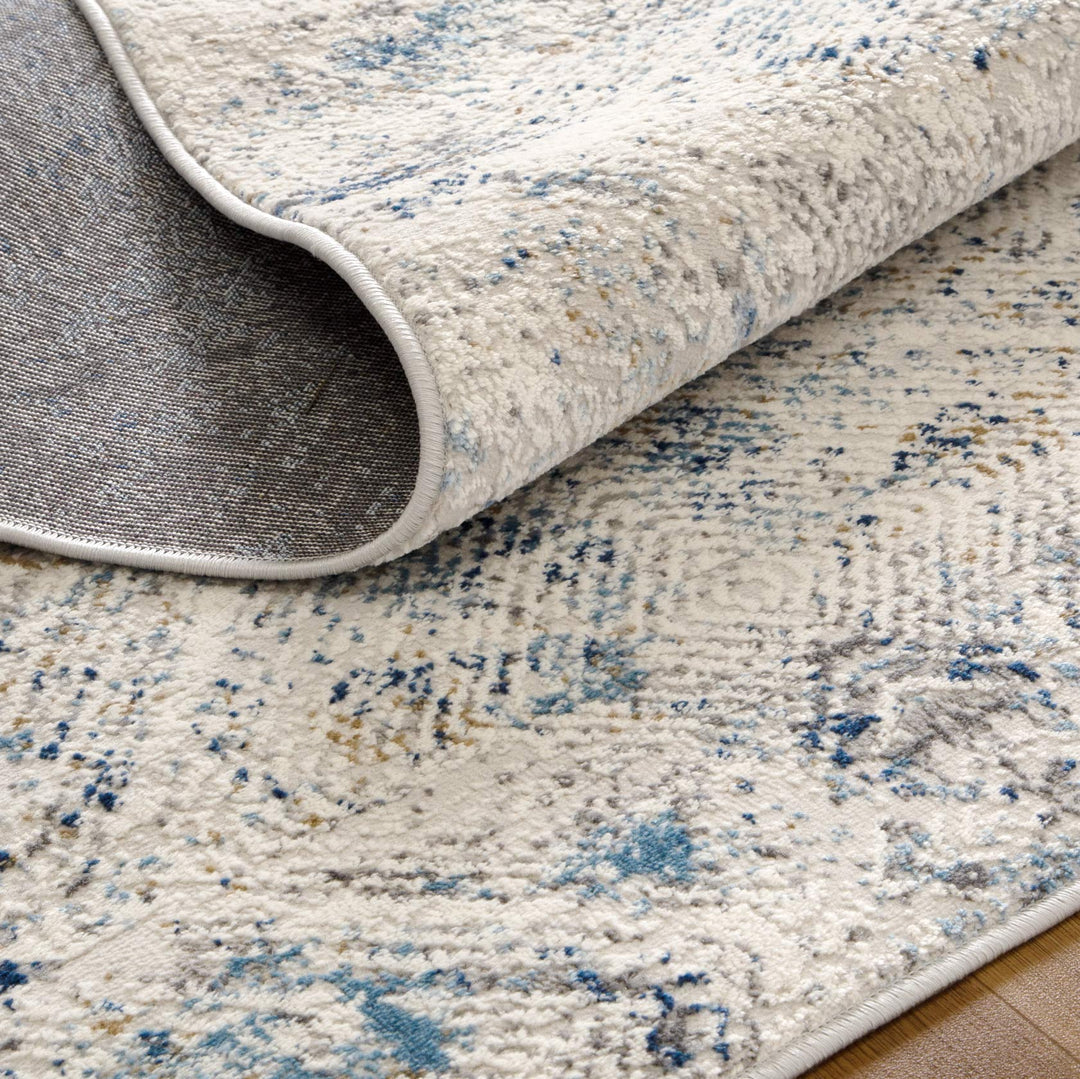 Textured area rug with modern abstract blue, grey, and beige pattern on a wooden floor