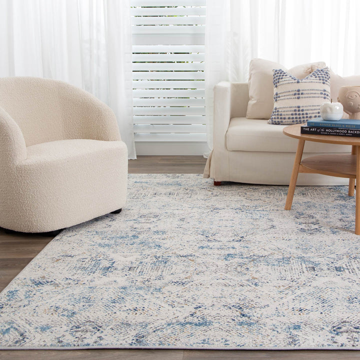 Modern living room with cream accent chair, sofa, coffee table, and blue patterned area rug