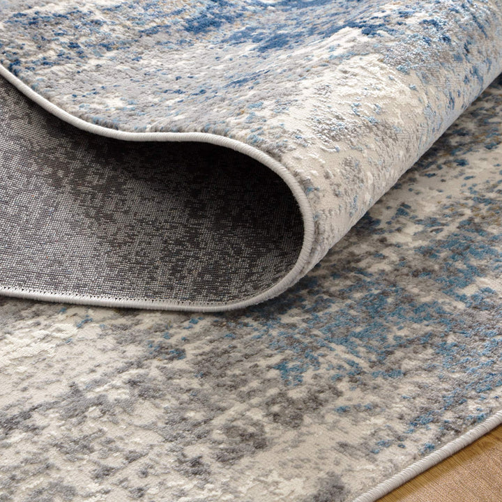 Modern area rug with blue, grey, and beige abstract pattern and soft textured surface