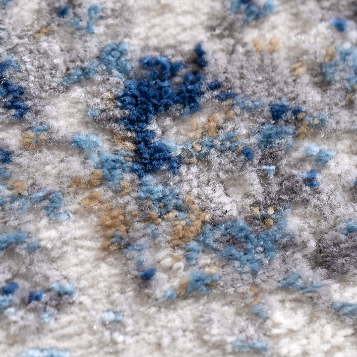 Close-up of textured area rug with blue, gray, and beige abstract pattern