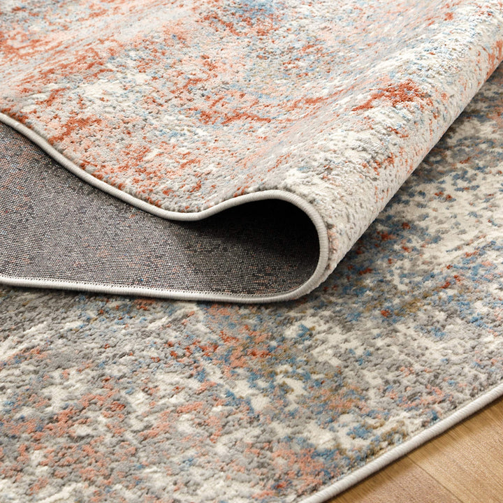 Close-up of a textured area rug with modern abstract pattern in grey, orange, and blue tones