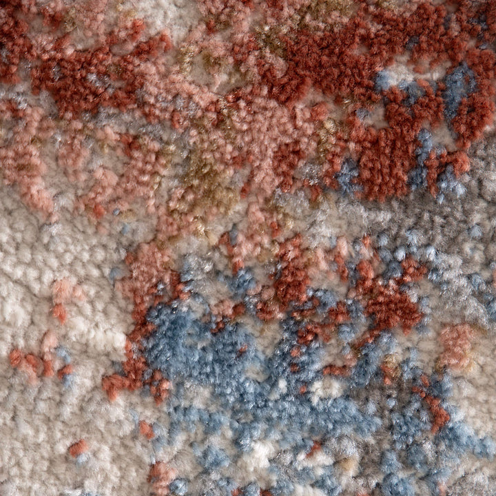Close-up of textured area rug with blue, rust, beige, and cream abstract pattern