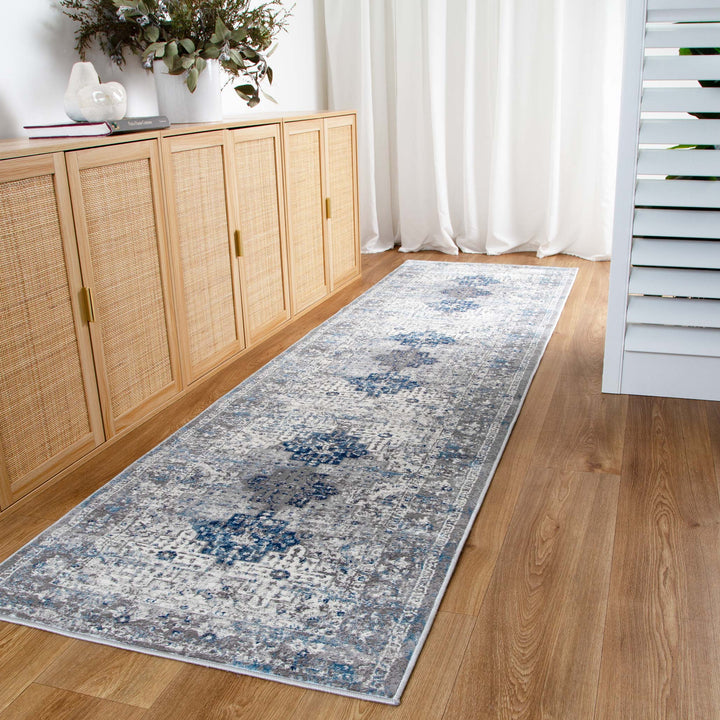 Blue and gray patterned hallway runner rug on wooden floor with rattan sideboard