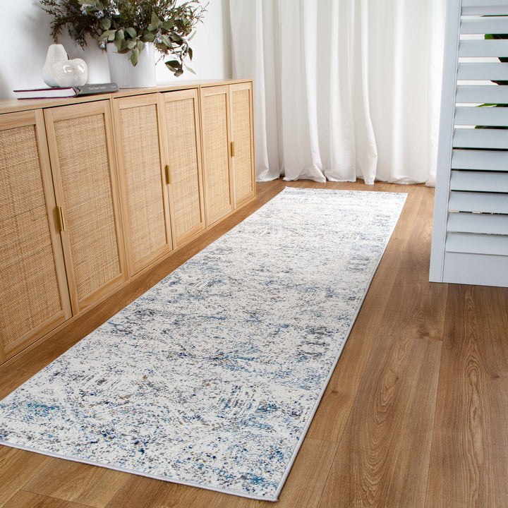 Long hallway runner rug with blue and grey pattern on wood floor beside modern sideboard