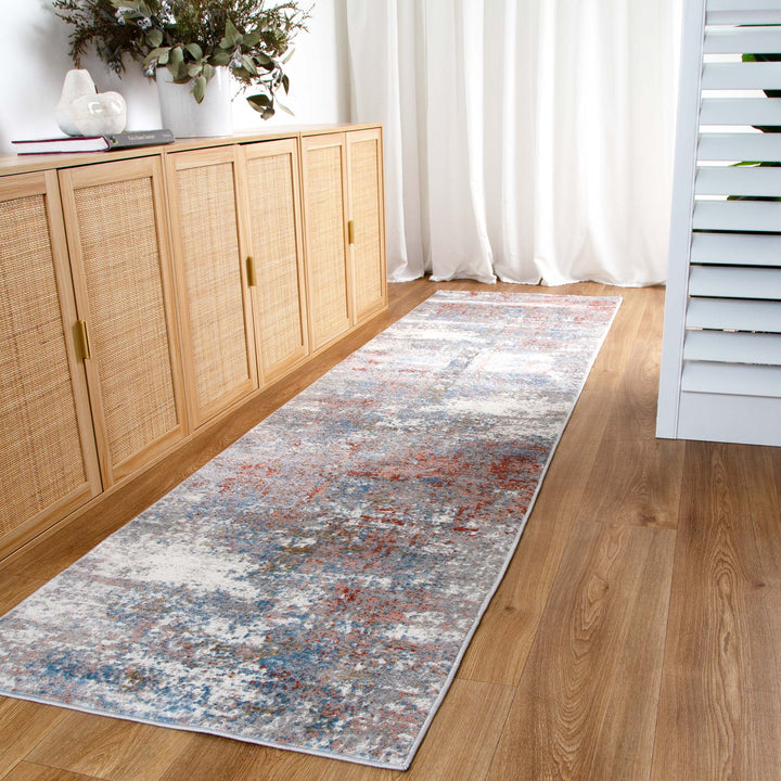 Modern abstract hallway runner rug with blue and red tones on wood floor