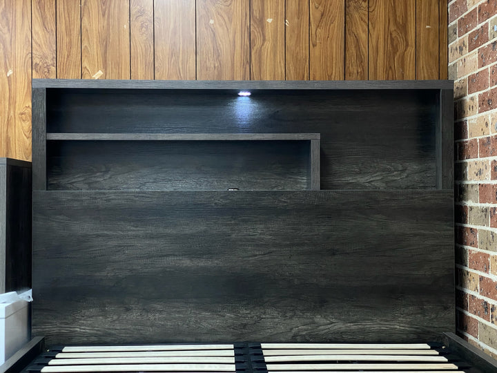 Modern dark wood bed headboard with shelves and built-in LED light against a wood panel wall