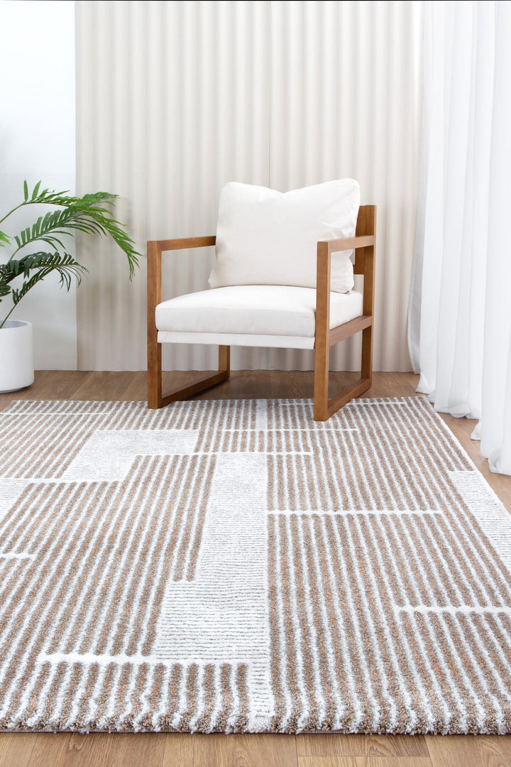 Modern wooden armchair with white cushions on geometric beige and white area rug, indoor setting