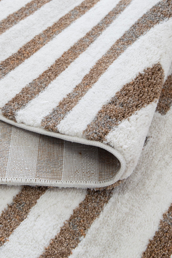 Close-up of a modern area rug with textured brown and beige stripes on a white background