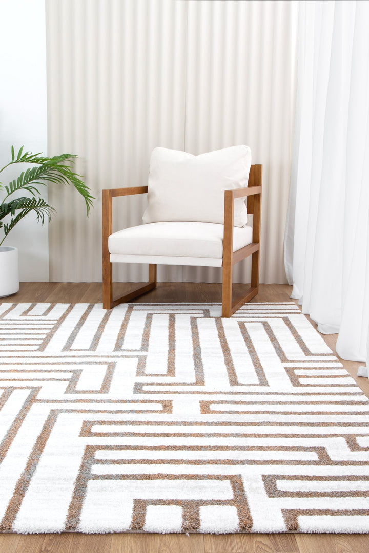 Modern wooden armchair with white cushions on geometric patterned area rug in bright living room