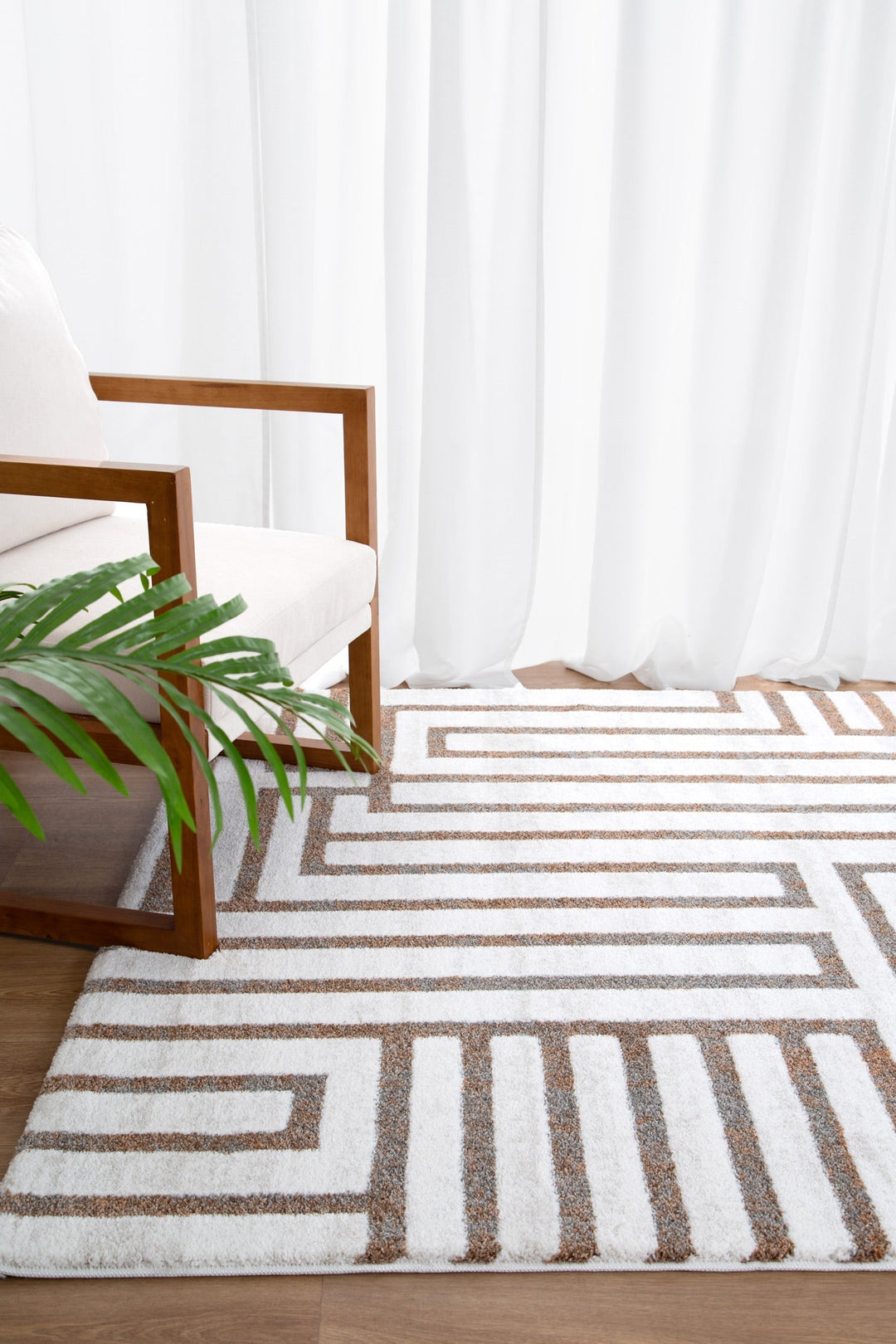 Modern armchair with wooden frame next to geometric patterned area rug on wood floor