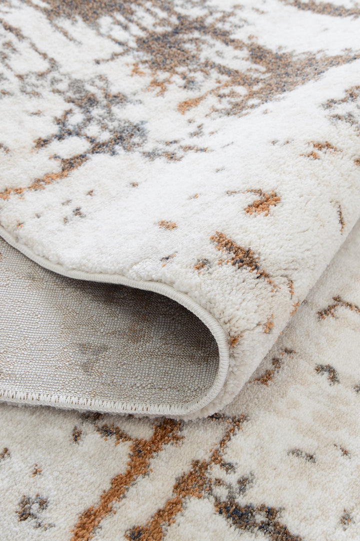 Textured cream area rug with abstract brown and gray pattern, soft pile close-up