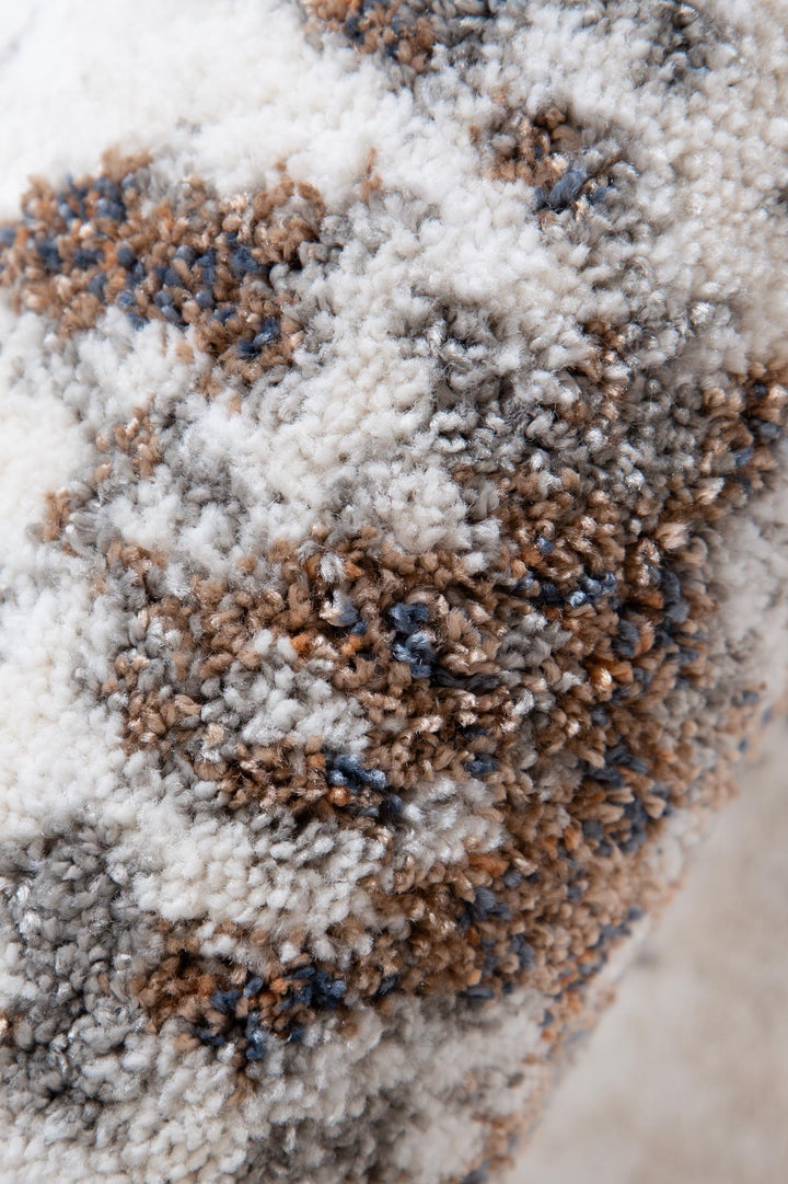 Close-up of plush patterned rug with white, brown, and gray textured fibers.