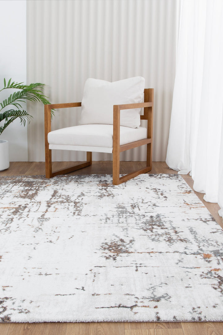 Modern wood armchair with white cushions on abstract patterned area rug in bright living room