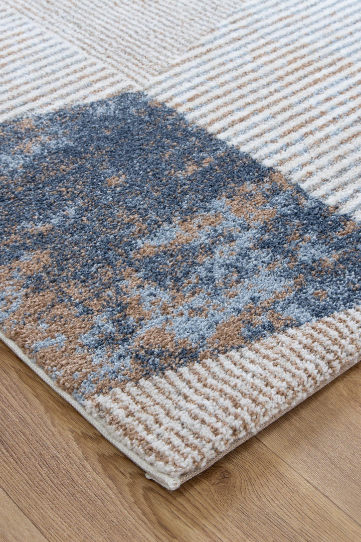 Modern area rug with beige, blue, and gray geometric patterns on wooden floor