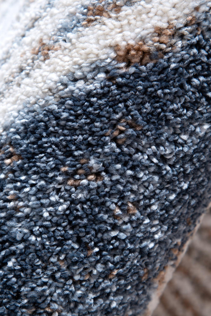Close-up of textured multicolor area rug with blue, beige, and white yarns.