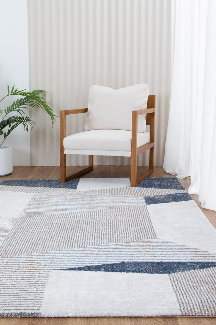 Modern wooden armchair with white cushions on geometric patterned area rug in cozy living room