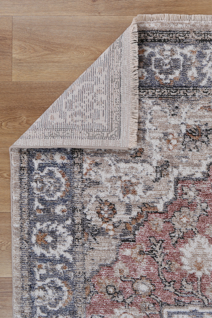 Corner of a vintage-style area rug with ornate floral patterns on wooden floor