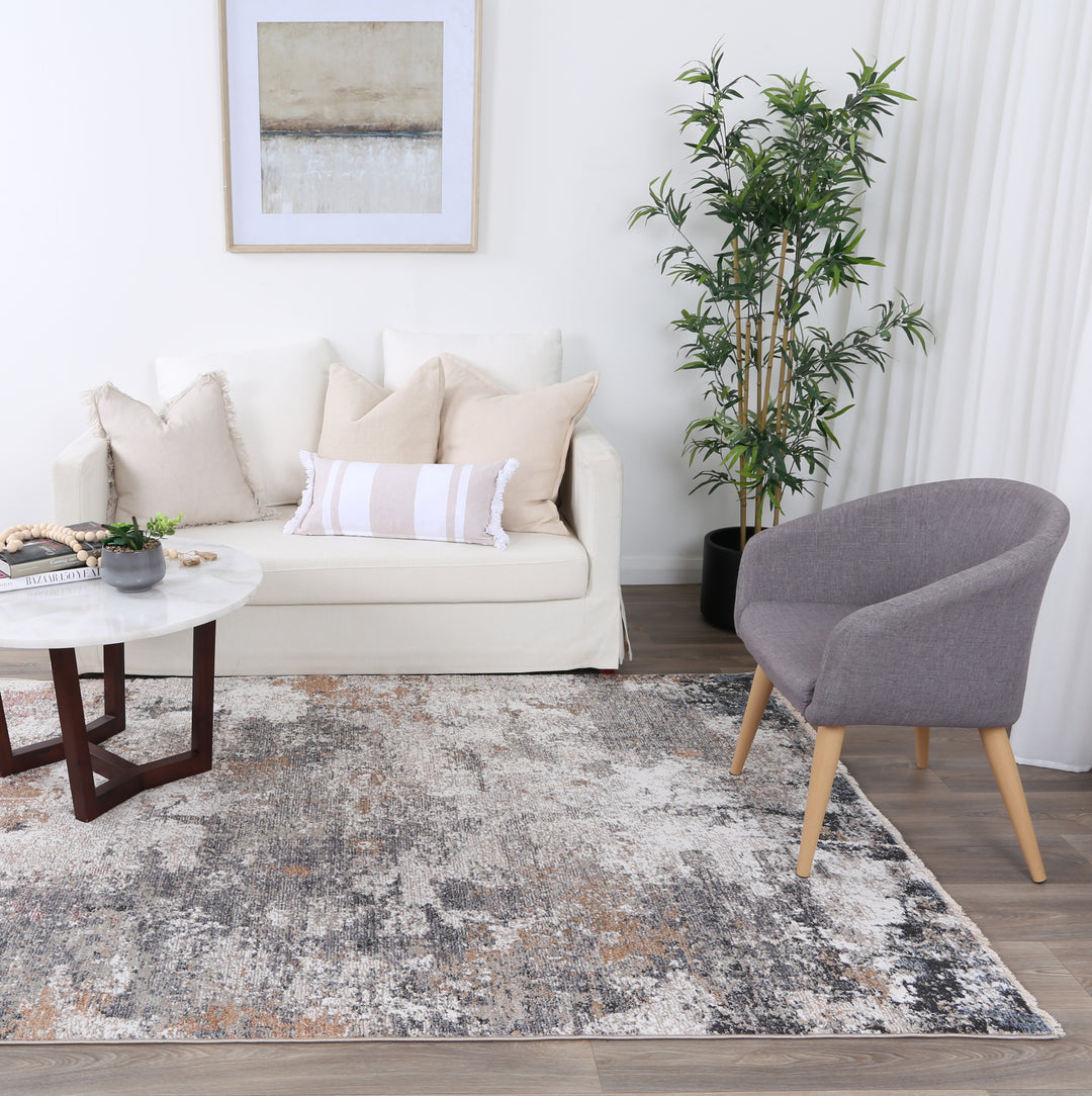 Modern living room with cream sofa, gray accent chair, abstract rug, coffee table, and potted plant