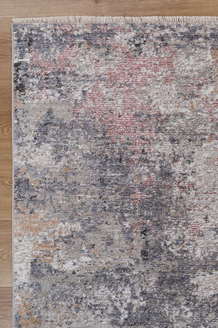 Modern area rug with abstract grey, beige, and pink pattern on wood floor