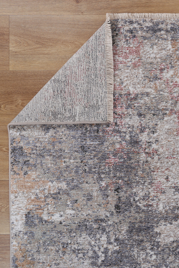 Modern abstract area rug with a textured pattern on wood flooring, corner flipped to show backing