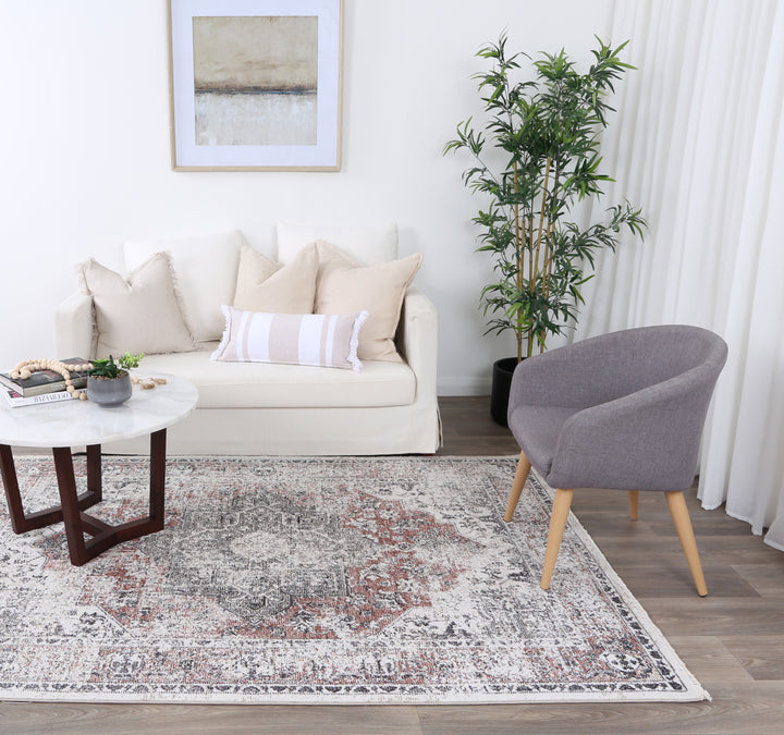 Modern living room with cream sofa, accent pillows, gray chair, marble coffee table, and patterned rug