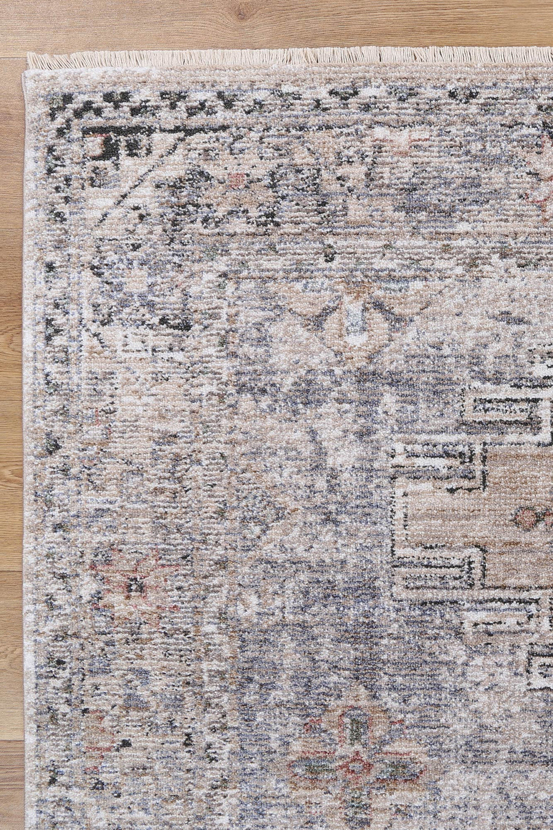 Beige and grey area rug with vintage distressed pattern on wooden floor