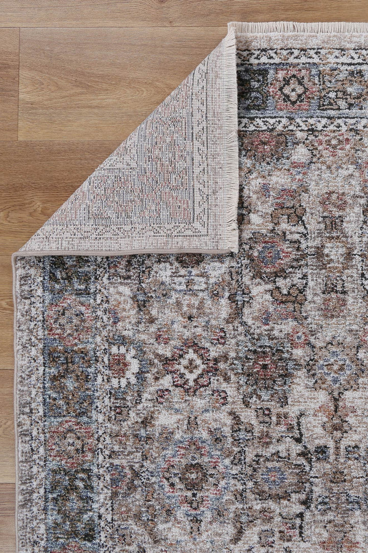 Traditional floral patterned area rug with beige, brown, and blue tones on wood floor