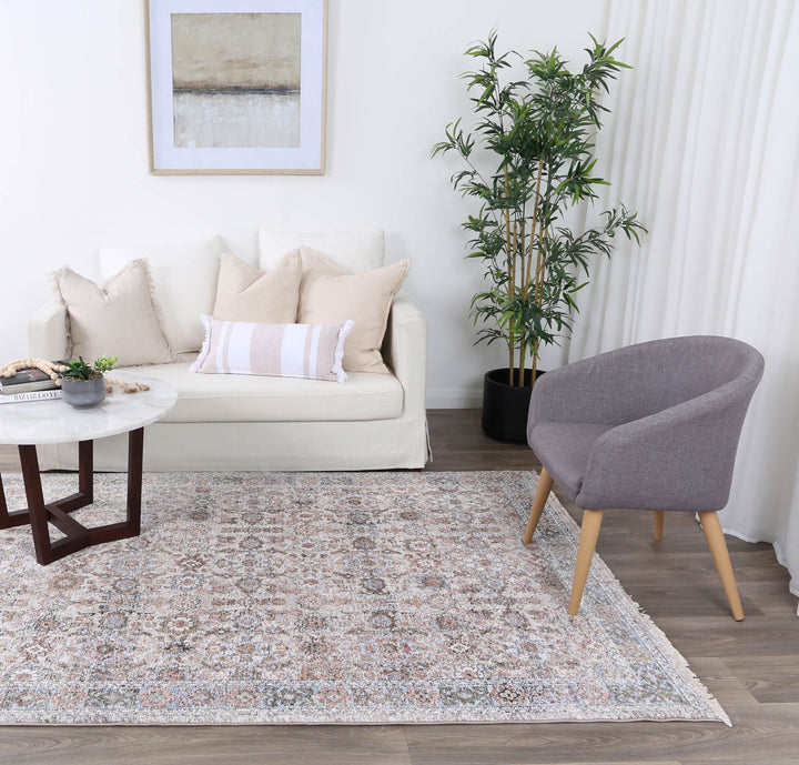 Modern living room with cream sofa, decorative pillows, gray chair, patterned area rug, and marble coffee table