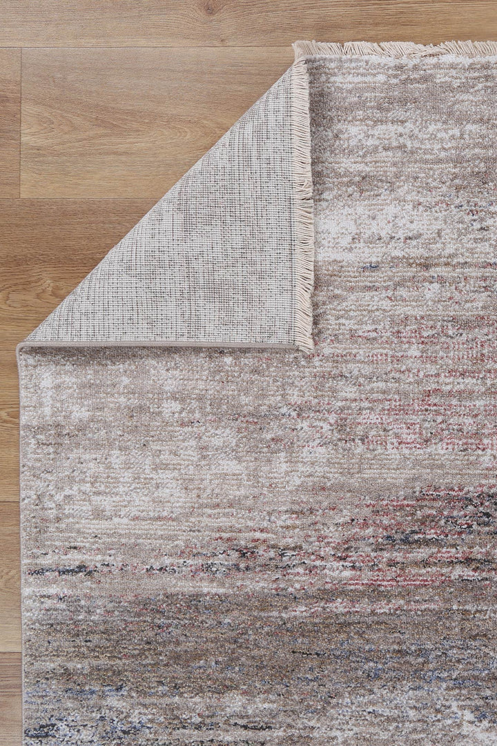 Textured area rug with beige, brown, and muted red tones on wooden floor