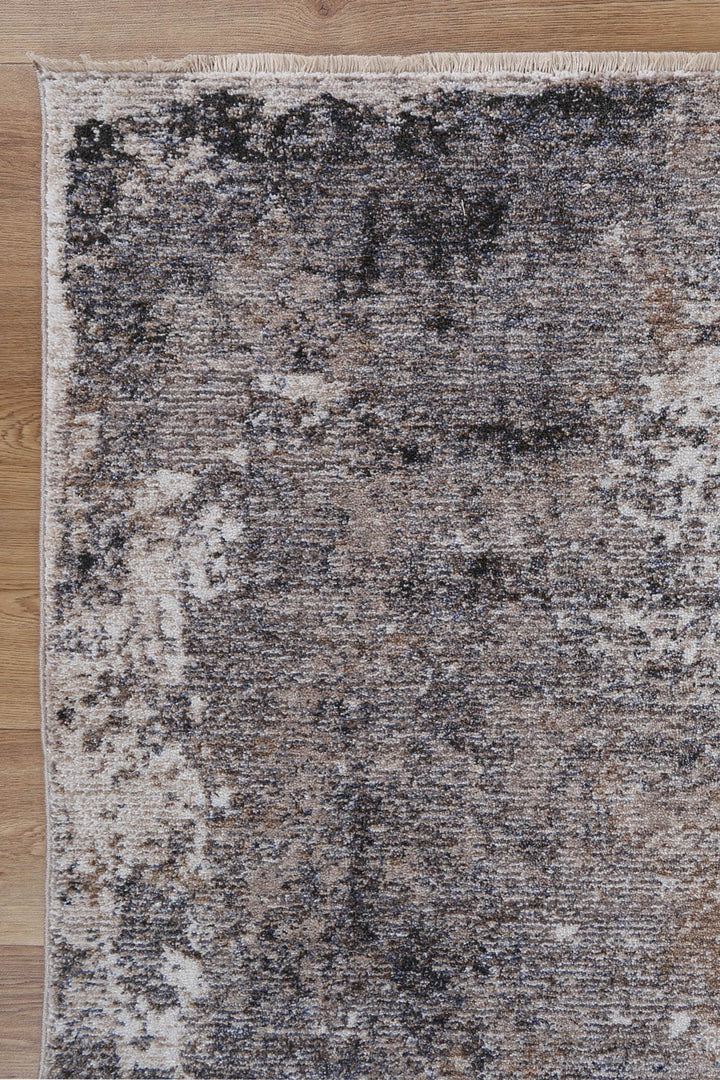 Close-up of a modern area rug with a distressed beige and brown pattern on wooden floor