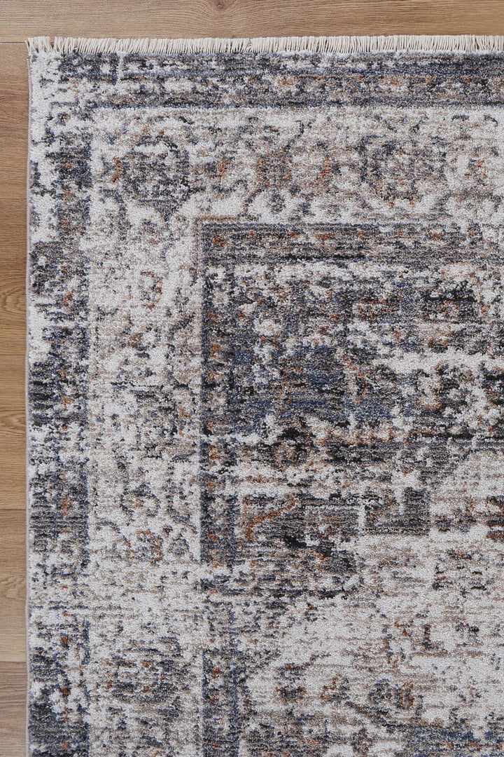 Distressed vintage area rug with gray, beige, and rust tones on wooden floor