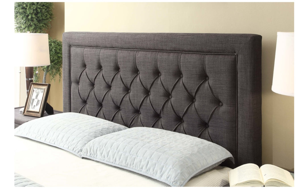 Gray upholstered tufted headboard with pillows, bedside lamps, and home decor