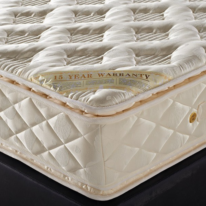 Close-up of a plush, quilted cream mattress with a 15 year warranty label, home furniture