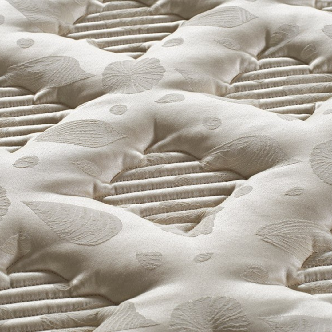 Close-up of a quilted beige mattress surface with leaf pattern texture