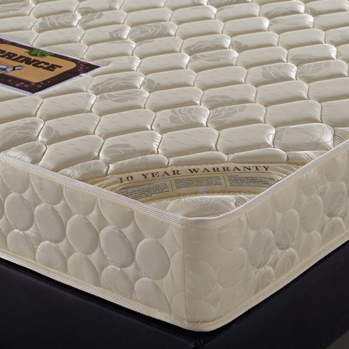 Close-up of a quilted beige mattress with 10-year warranty label, placed on a bed base
