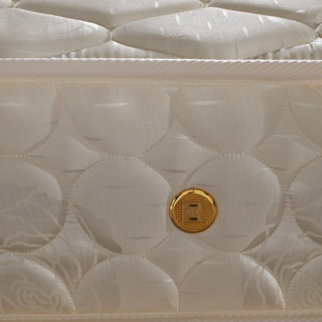 Close-up of a quilted cream mattress with a gold air vent and patterned stitching