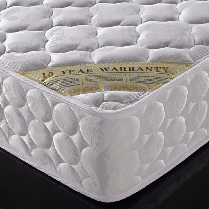 Close-up of a white luxury mattress with quilted pattern and a visible 15-year warranty label
