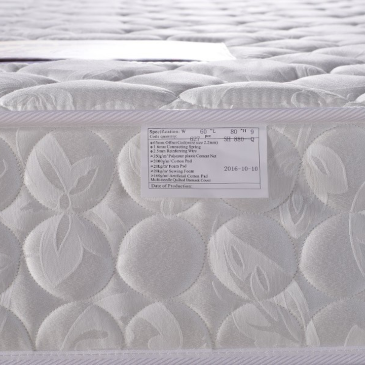 Close-up of a white quilted mattress with product label and stitched pattern