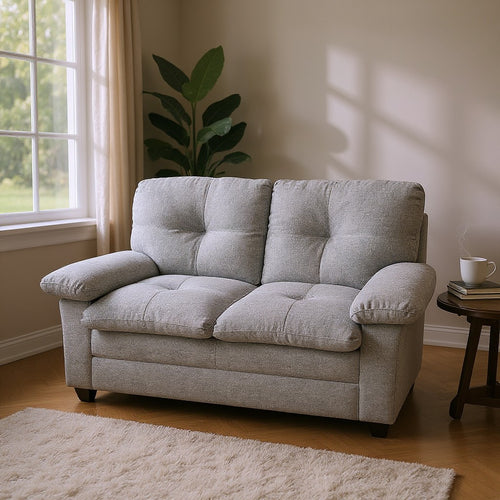 Gray tufted loveseat sofa in cozy living room with window and plant
