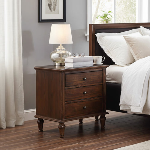 Wooden nightstand with three drawers beside bed, topped with lamp, books, and mug in bedroom