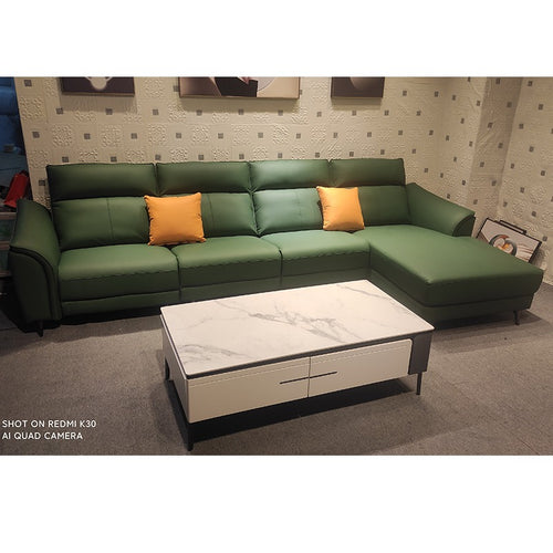 Green leather L-shaped sectional sofa with orange pillows and marble-top coffee table in Sydney furniture showroom