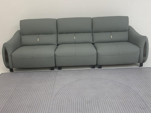 Modern gray leather sofa with three seats and sleek armrests, displayed on patterned rug