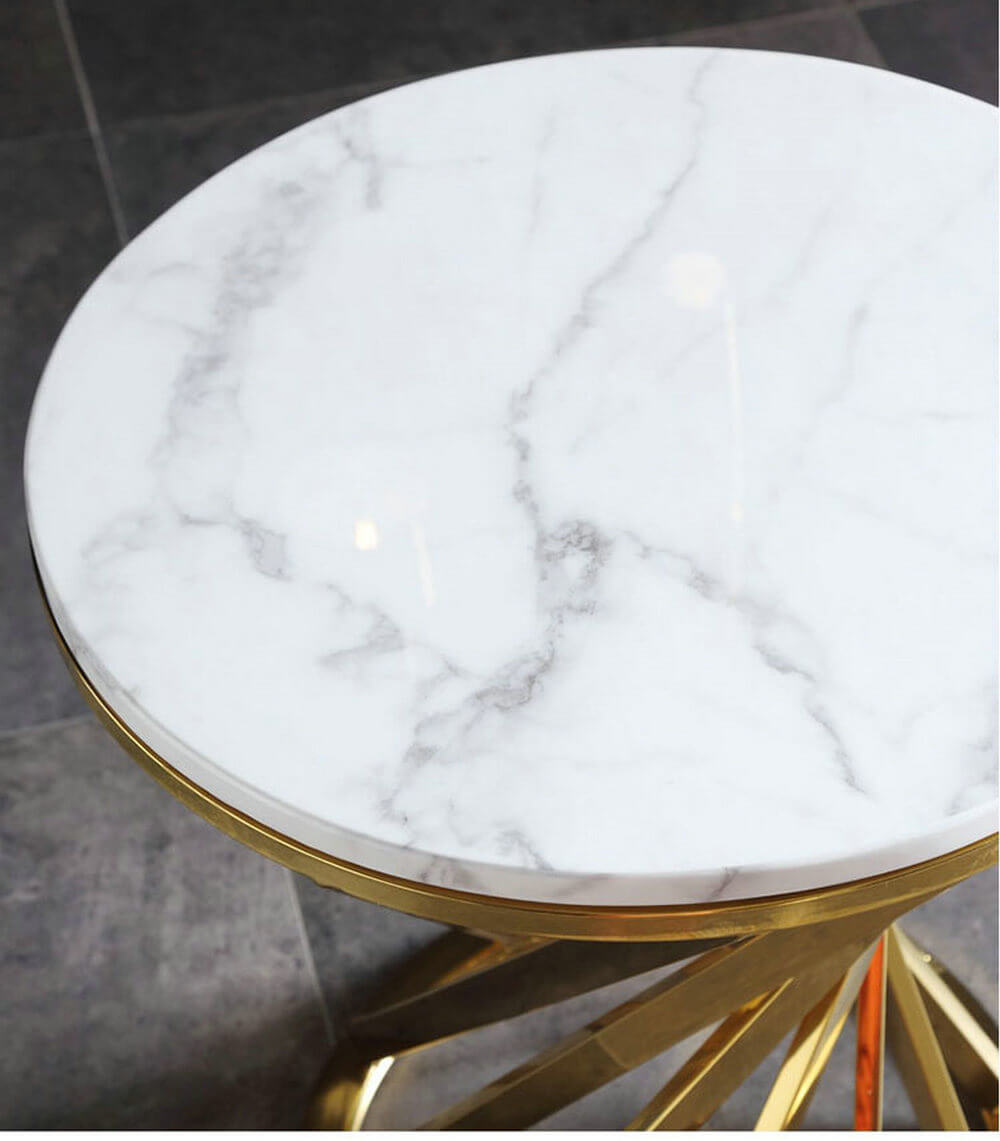 Round white marble side table with gold metal base on a tiled floor