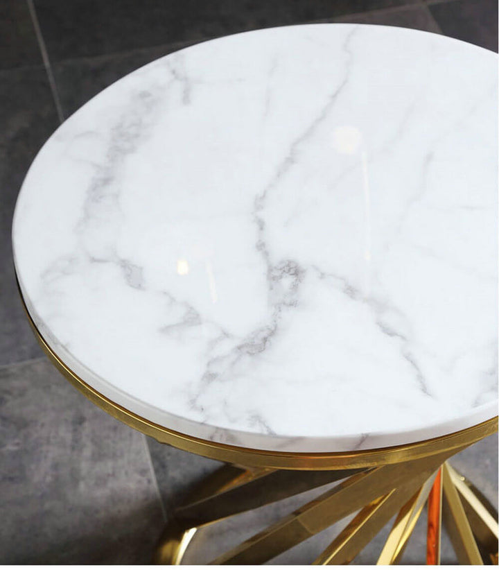 Round white marble side table with gold metal base on a tiled floor