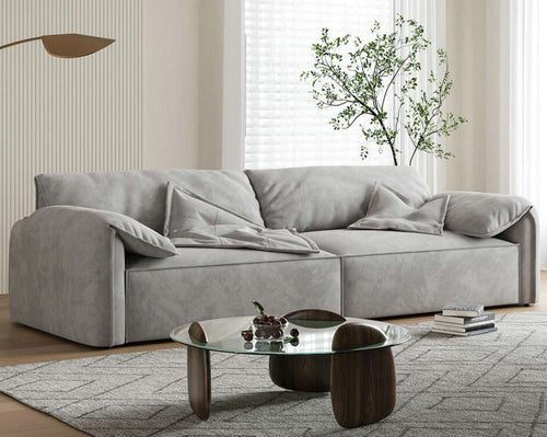 Modern gray fabric sofa with plush cushions in a stylish living room, paired with glass coffee table and rug.