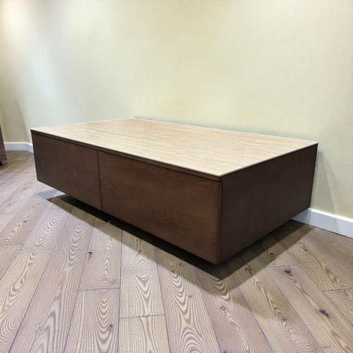 Modern rectangular wooden coffee table with drawers on a wood floor against a beige wall
