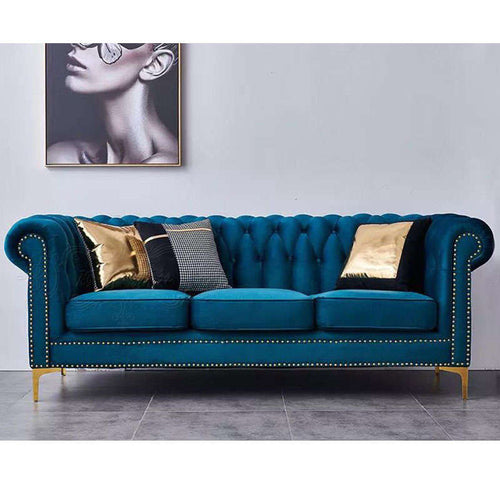 Luxury teal velvet Chesterfield sofa with gold legs and nailhead trim, styled with decorative pillows.