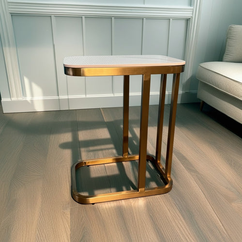 Modern gold metal side table with white top in a bright living room setting