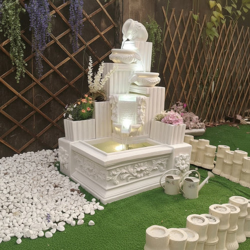 Elegant white tiered garden fountain with LED lights, floral accents, and pebble surround for outdoor decor
