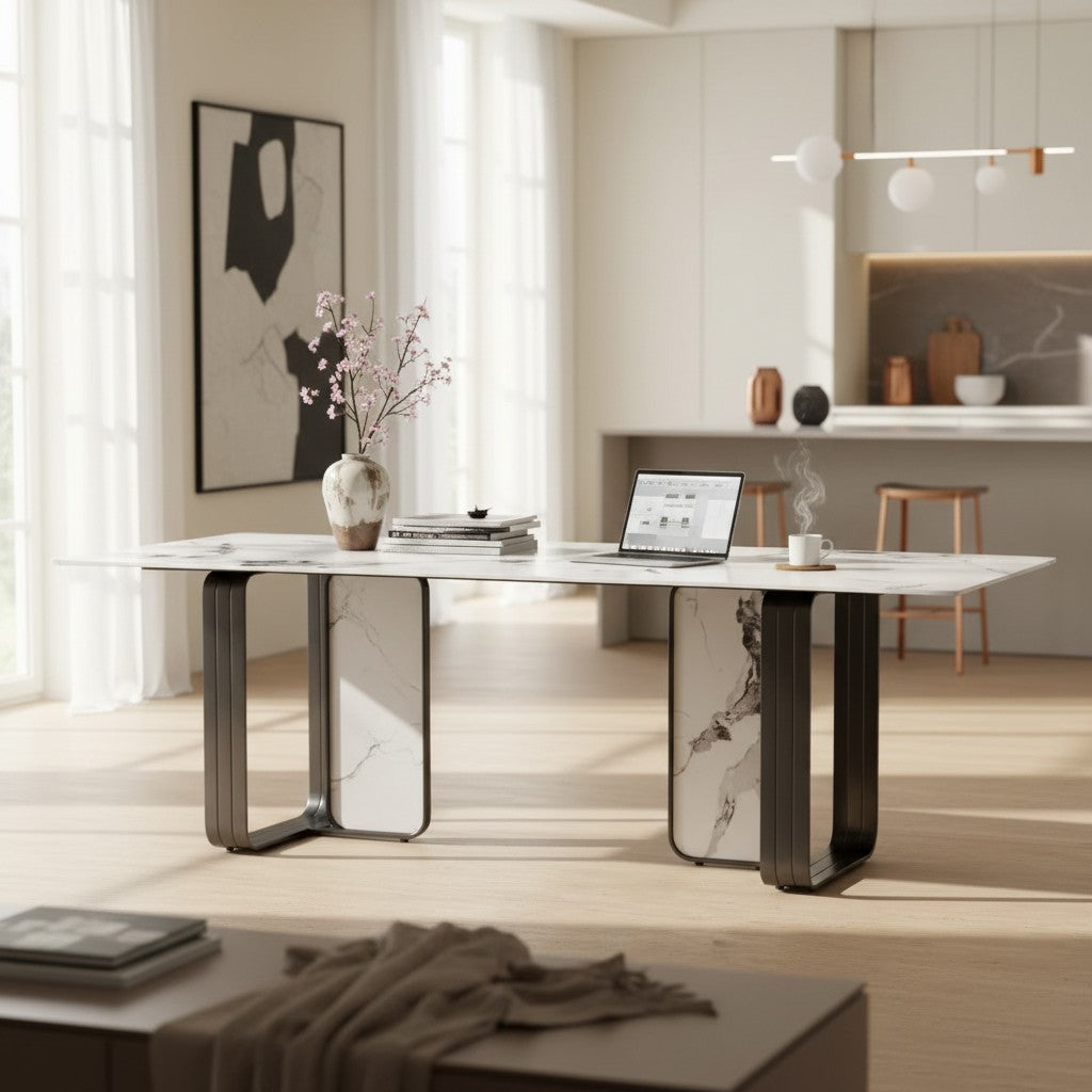 Modern marble dining table with a laptop, vase, and books in a bright, contemporary kitchen.